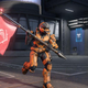 A Spartan in an orange power armor runs with a flag in Halo Infinite.